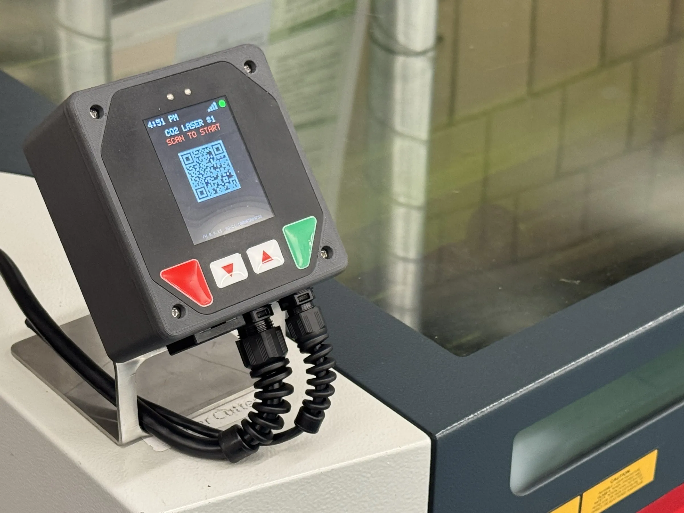 The MakerOps controller mounted on a Trotec laser cutter, showing a scan-to-start code